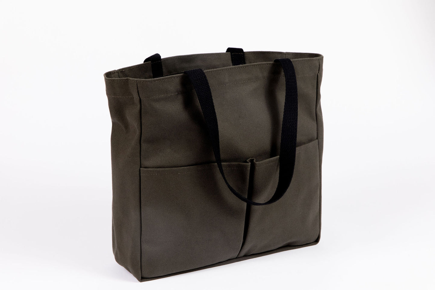 Olive canvas tote bag with two front pockets and black webbing handles, shown at a three-quarter angle
