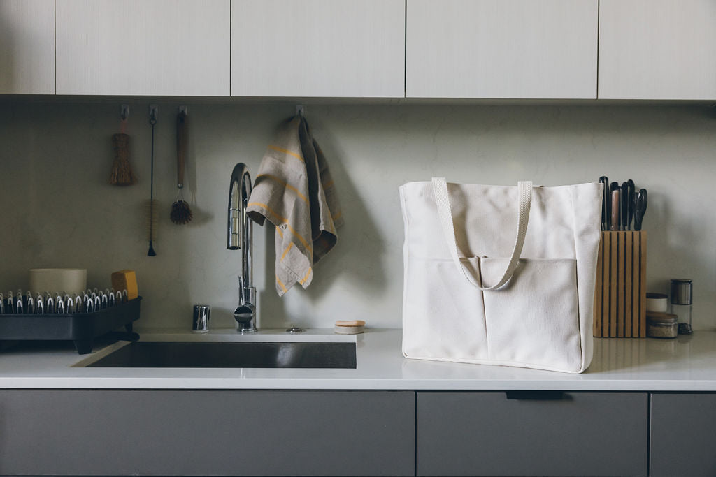 Natural canvas Utility Carryall tote on a kitchen counter with utensils and a sink in the background
