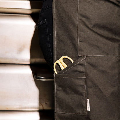Yellow-handled scissors tucked into the front pocket of a pine canvas apron with the EH·Works label