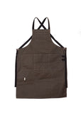 Pine canvas apron with multiple pockets and adjustable crossback straps, laid flat on a white background