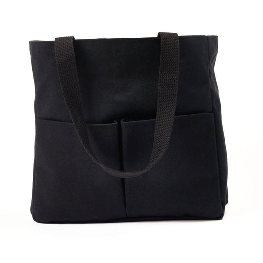 Black canvas tote bag with two wide shoulder straps and two front utility pockets, shown against a white background
