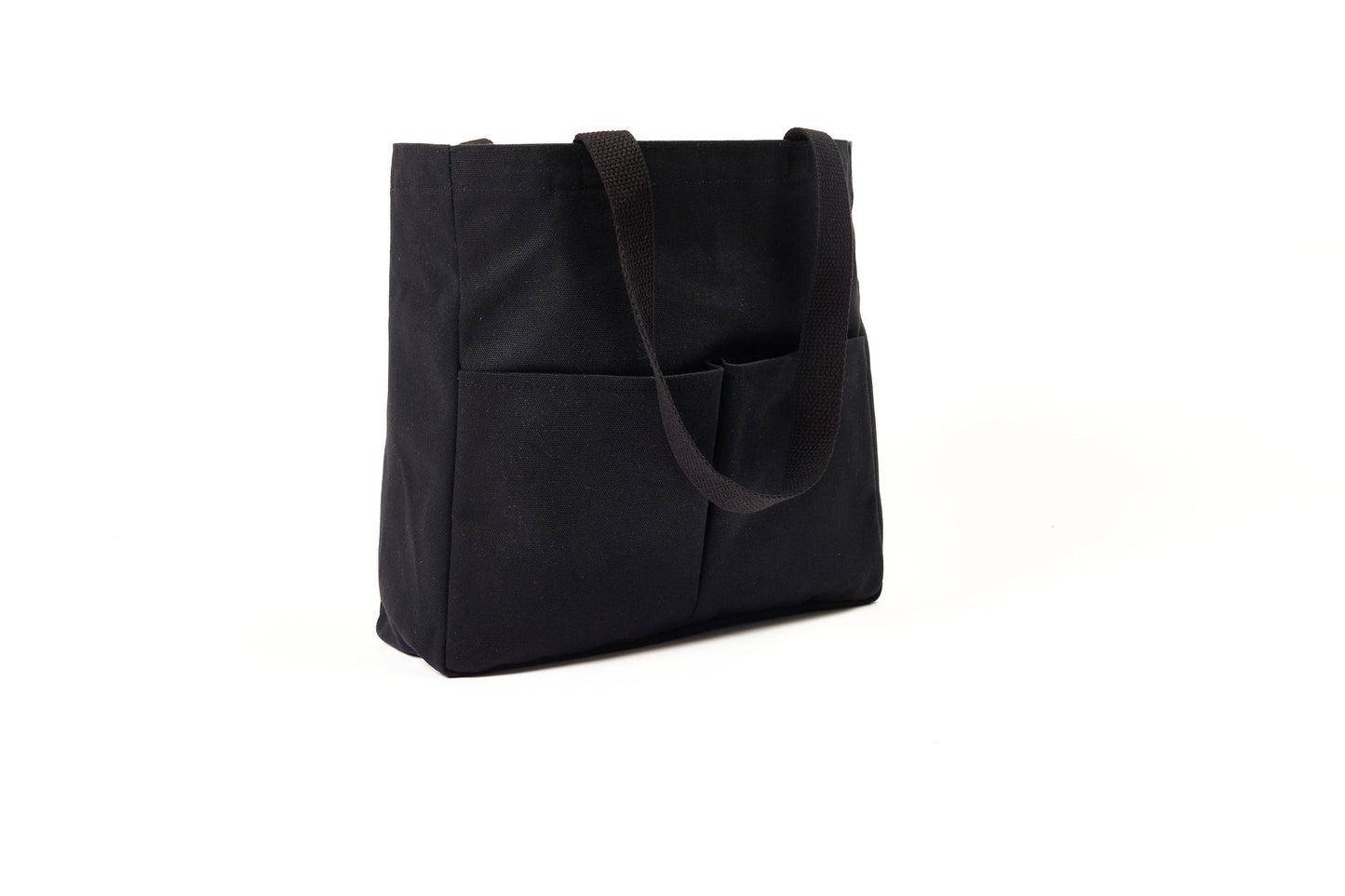 Black canvas Utility Carryall tote with two shoulder straps and front pockets, photographed on a white background
