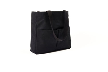 Black canvas Utility Carryall tote with two shoulder straps and front pockets, photographed on a white background
