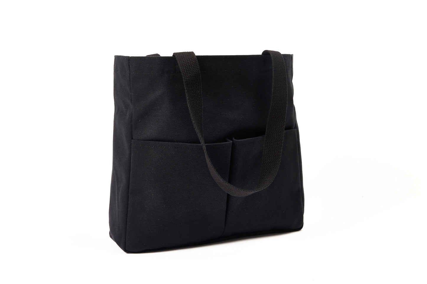 Black canvas Utility Carryall tote with two shoulder straps and front pockets, photographed on a white background
