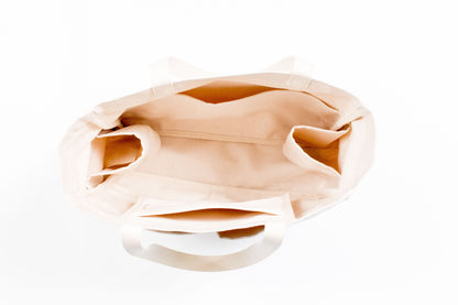Top-down view inside an empty natural canvas Utility Carryall tote, showing interior pockets