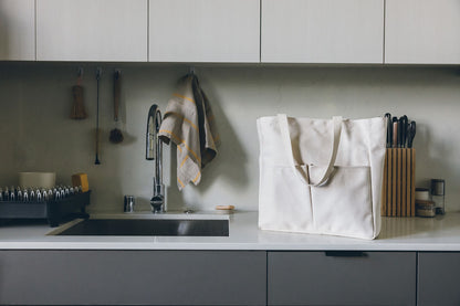 Natural canvas Utility Carryall tote on a kitchen counter with utensils and a sink in the background