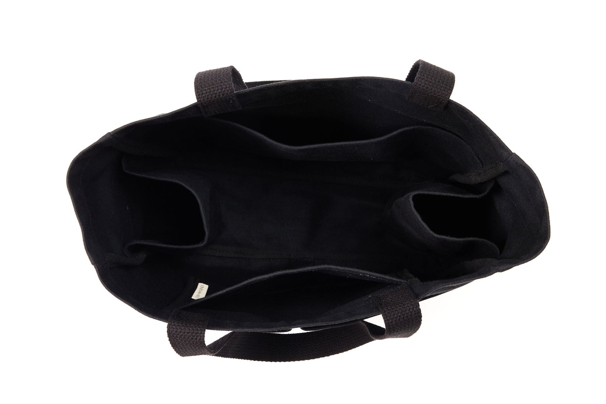 Top-down view inside an empty black canvas Utility Carryall tote, showing interior compartments and webbed handles
