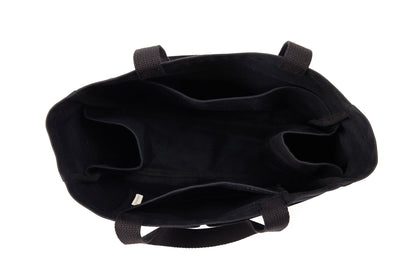 Top-down view inside an empty black canvas Utility Carryall tote, showing interior compartments and webbed handles
