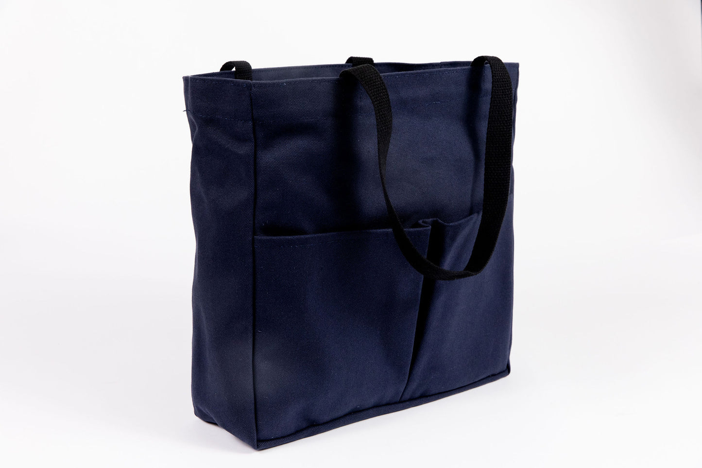 Canvas Utility Carryall tote in navy, three-quarter view showing front pockets and black webbing handles