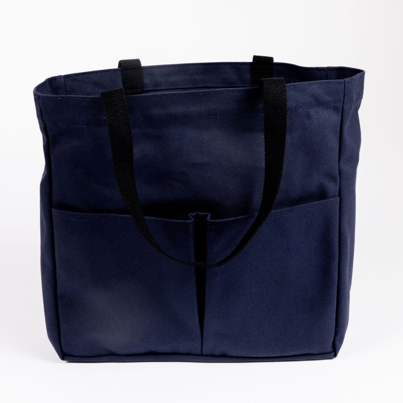 Canvas Utility Carryall tote in navy, with front pockets and black webbing handles, shown on a white background