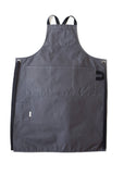 Grey canvas apron with multiple pockets and adjustable crossback straps, laid flat on a white background