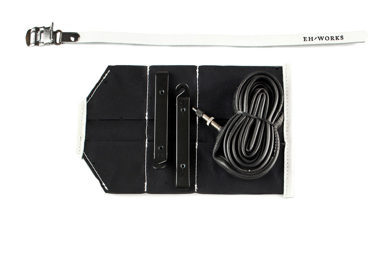 Open black canvas Sojourner tool roll with white leather trim, showing tire levers and a spare tube in the pockets