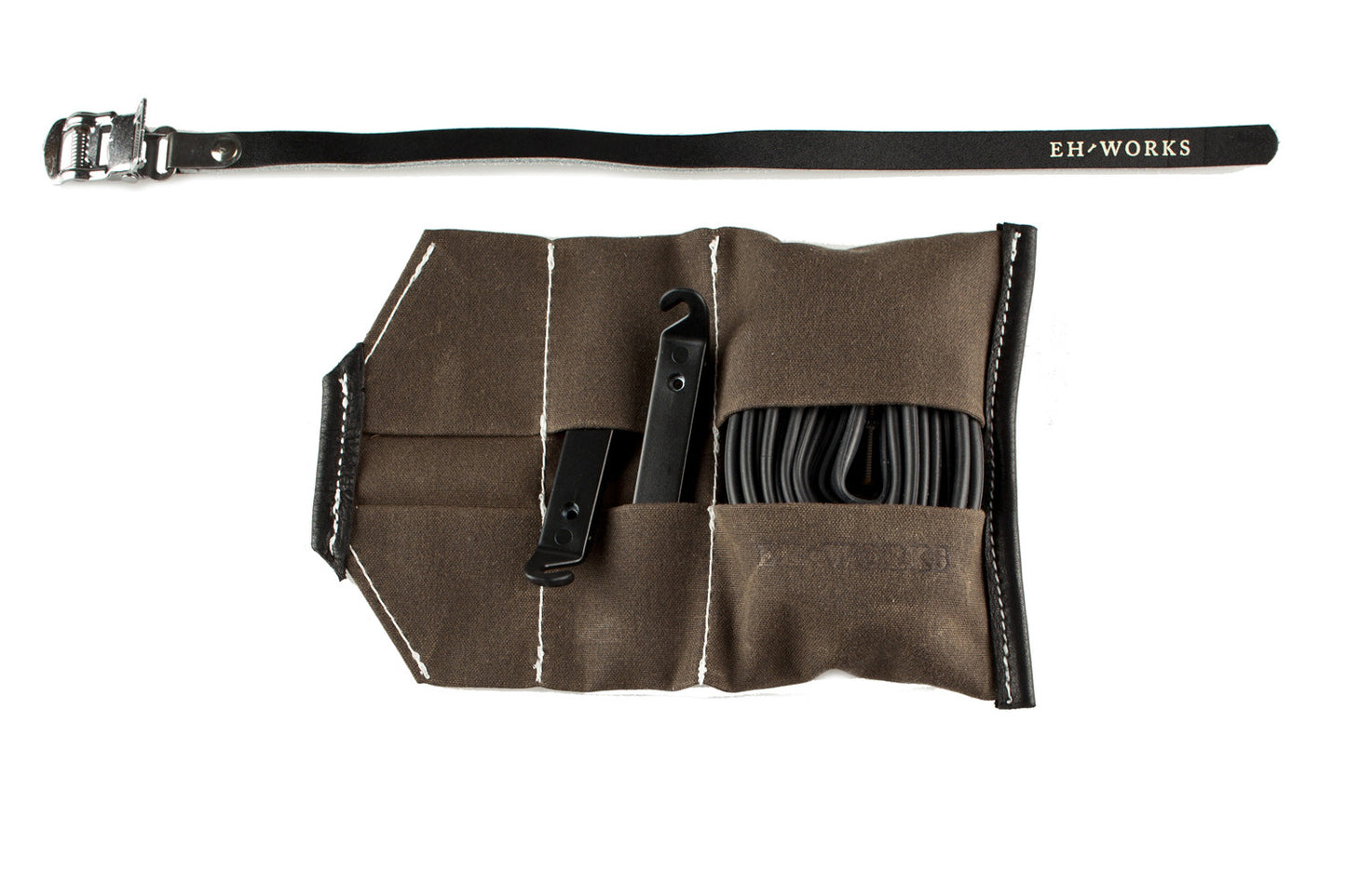 Open Sojourner tool roll in saddle brown canvas with black leather trim, showing tire levers and a spare tube in the pockets