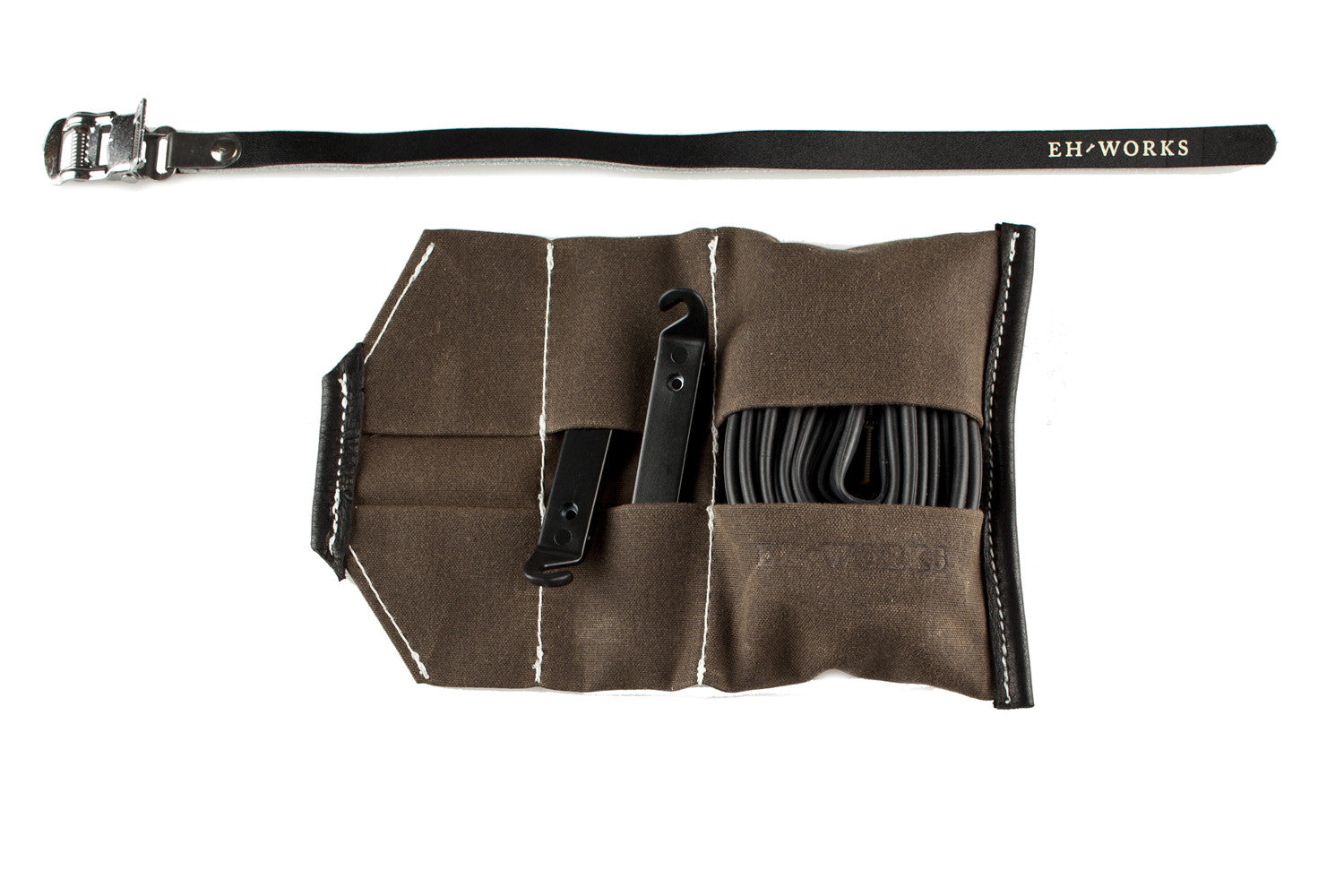 Open Sojourner tool roll in saddle brown canvas with black leather trim, showing tire levers and a spare tube in the pockets