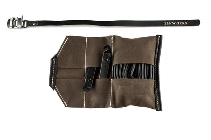 Open Sojourner tool roll in saddle brown canvas with black leather trim, showing tire levers and a spare tube in the pockets