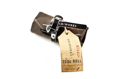 Sojourner tool roll in saddle brown canvas with black leather trim, rolled up with an EH·Works "Tool Roll" tag